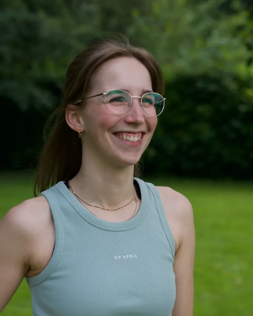Sara Felsberg lacht herzlich im Garten – Porträt mit Brille